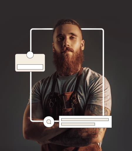 A ginger beard male barber with hand tattoos crossing his hands.