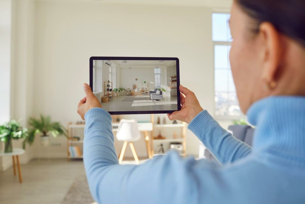 A real estate agent holding a tablet taking a photo of a living room