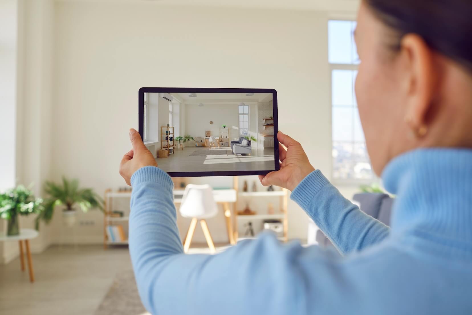 A real estate agent holding a tablet taking a photo of a living room